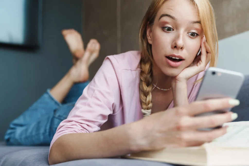 Young woman browsing interesting websites and apps on her smartphone while relaxing at home.