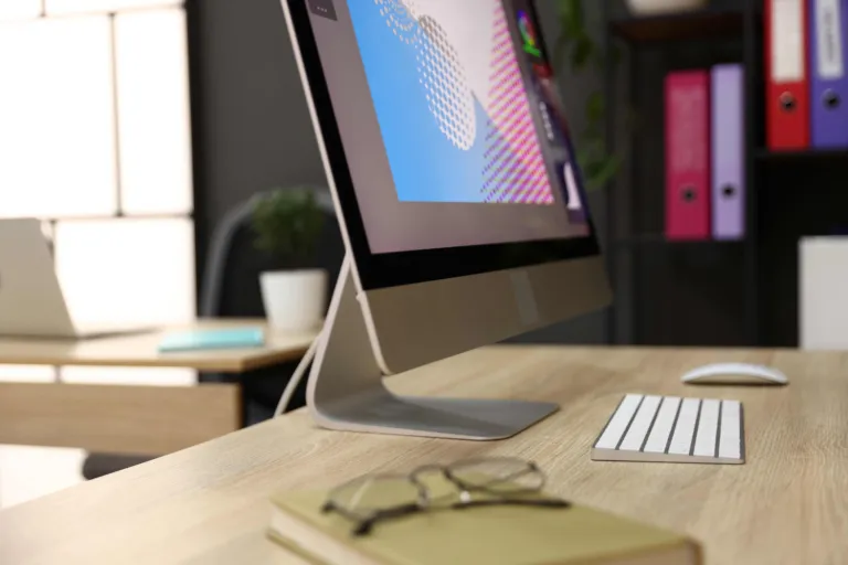 Modern computer monitor setup sitting on a clean wooden desk in a bright, well-lit workspace